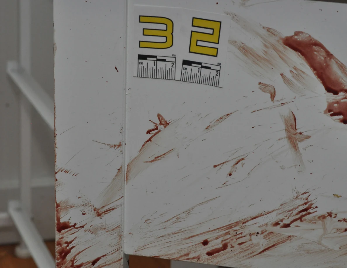 Reddish smears and streaks on a white cabinet beside scale label 32.