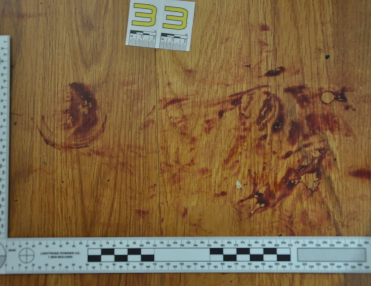 Reddish circular and smeared floor marks framed by measuring rulers beside scale label 33.