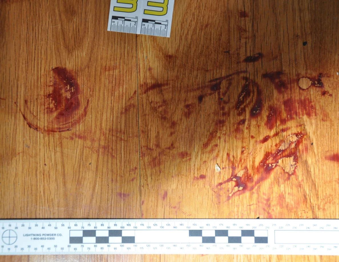 Reddish circular and smeared floor marks beside scale label 33 and a black-and-white measuring ruler.