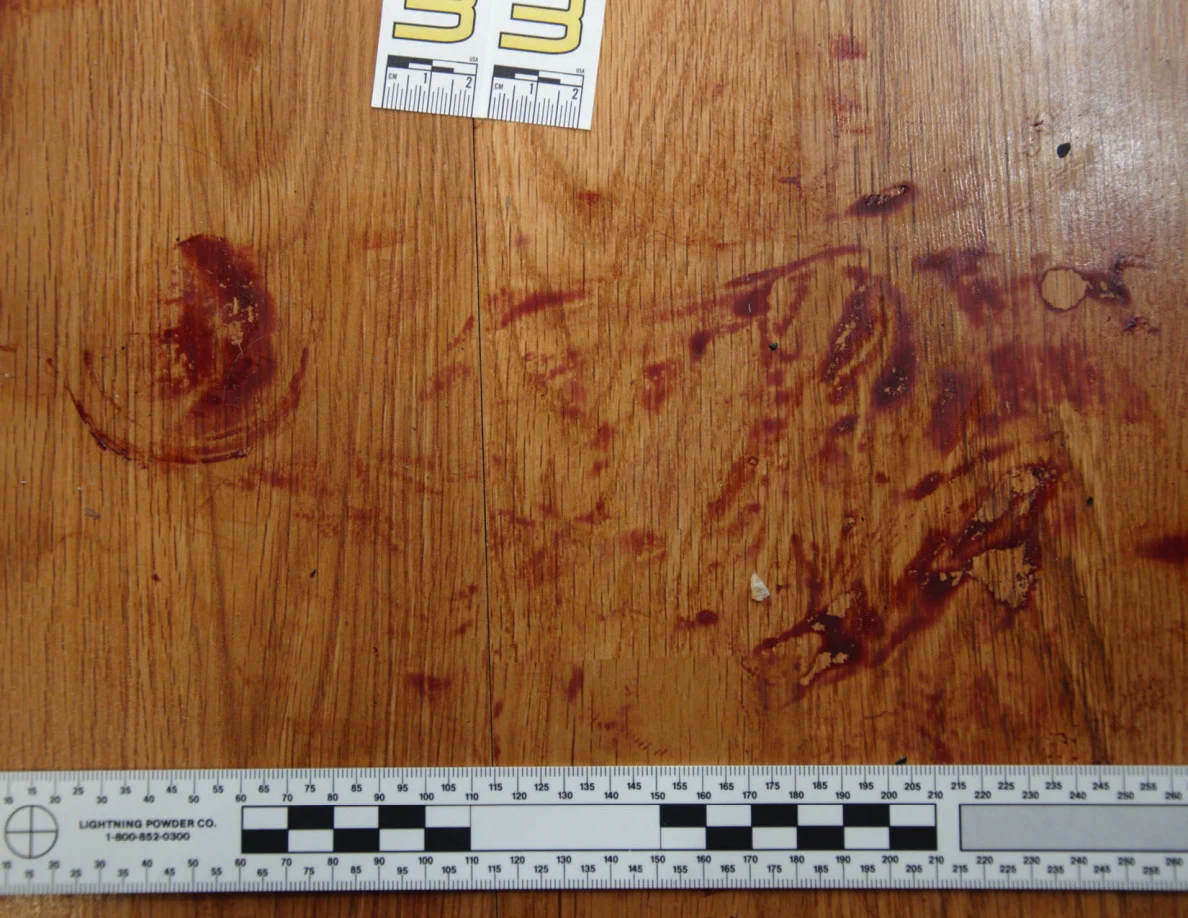 Reddish circular and smeared floor marks beside scale label 33 and a black-and-white measuring ruler.