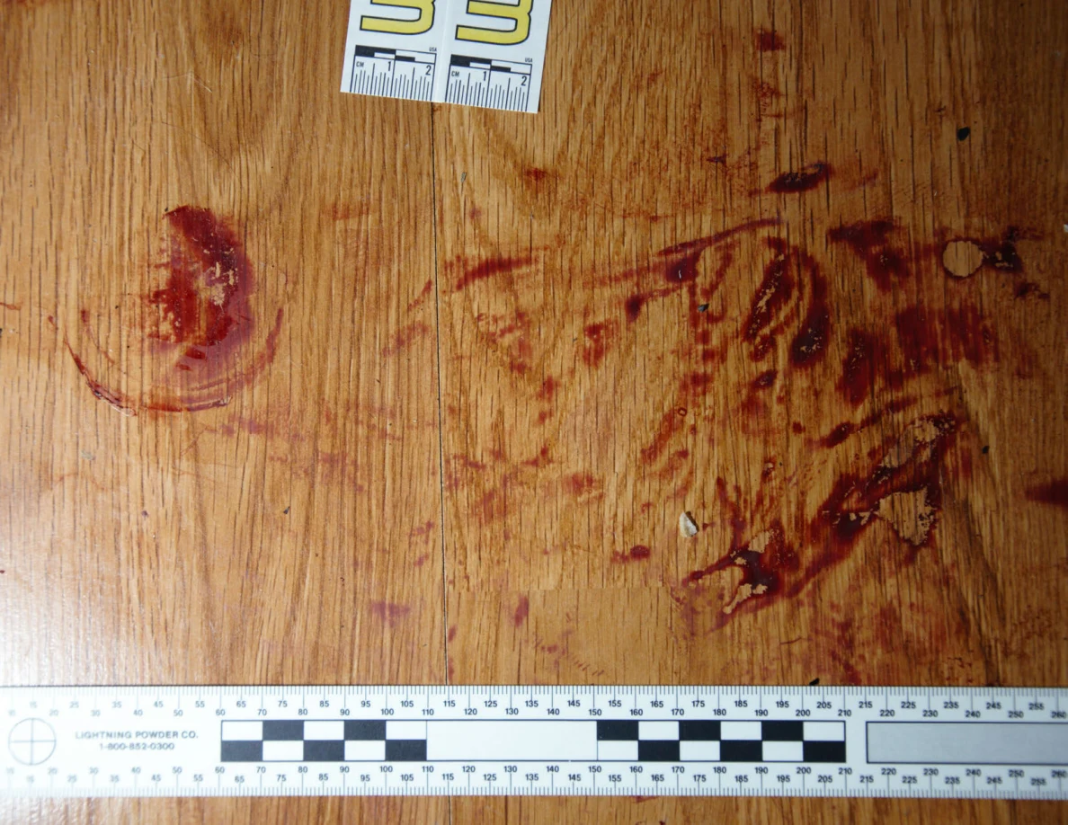 Reddish circular and smeared floor marks beside scale label 33 and a black-and-white measuring ruler.