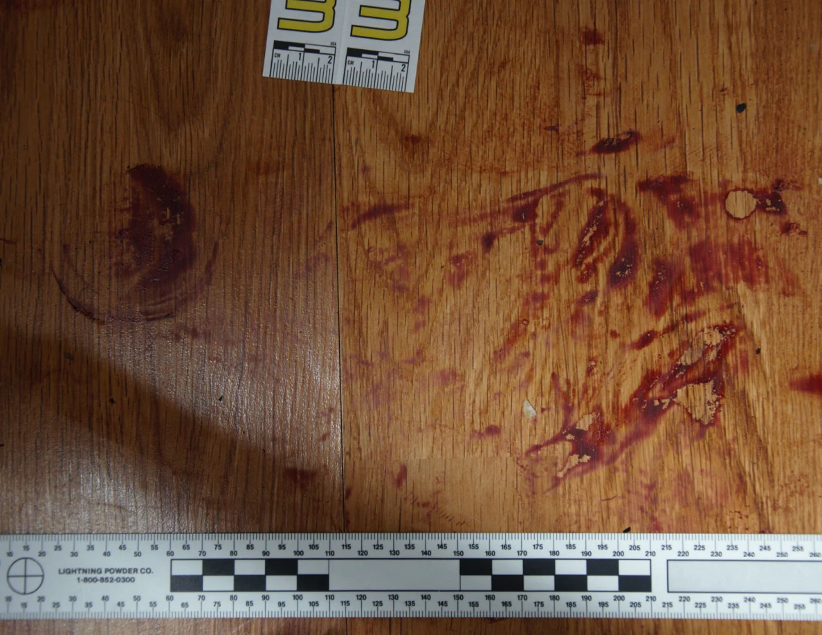 Reddish circular and smeared floor marks beside scale label 33 and a black-and-white measuring ruler.
