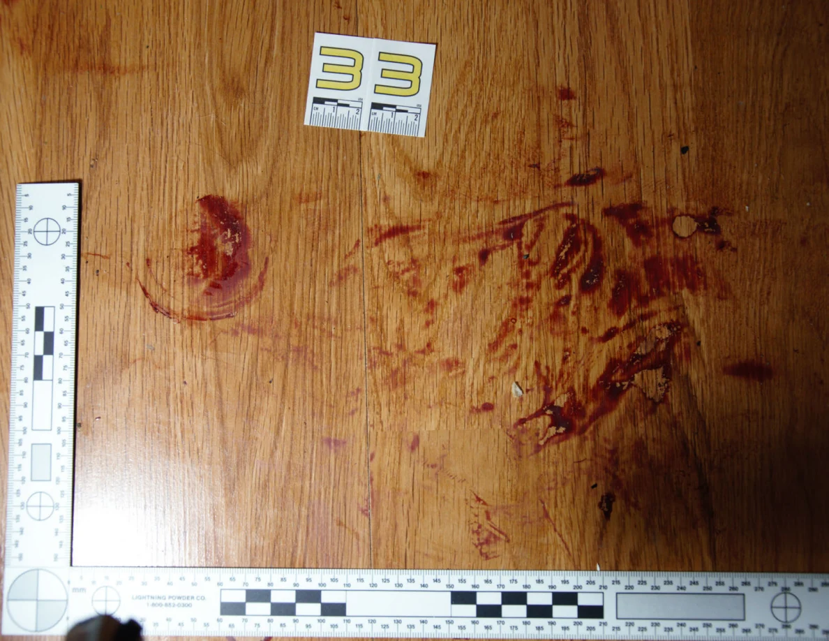 Reddish circular and smeared floor marks beside scale label 33 and measuring rulers.