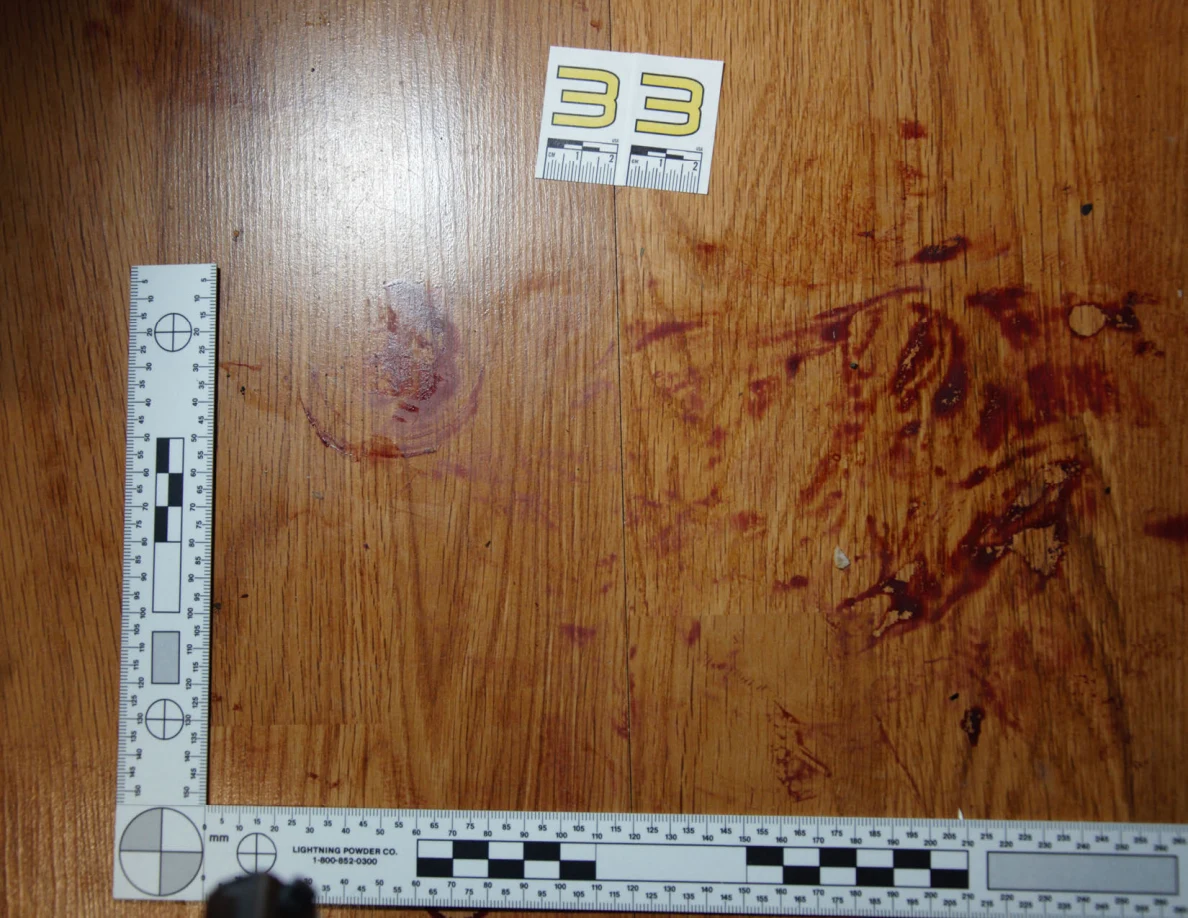Reddish circular and smeared floor marks beside scale label 33 and measuring rulers.