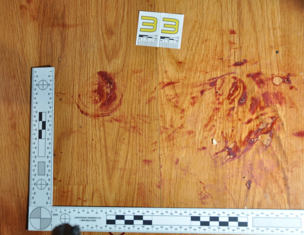 Reddish circular and smeared floor marks beside scale label 33 and measuring rulers.