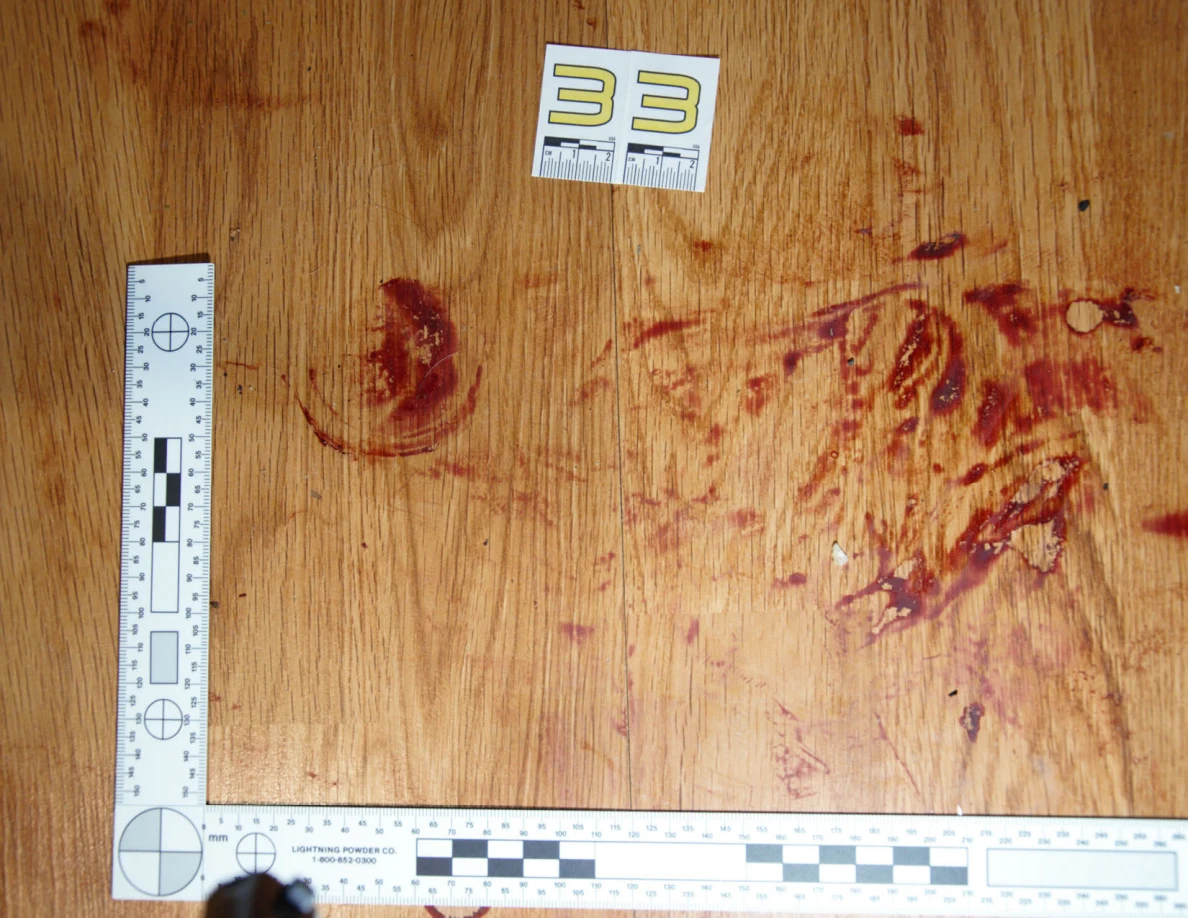 Reddish circular and smeared floor marks beside scale label 33 and measuring rulers.