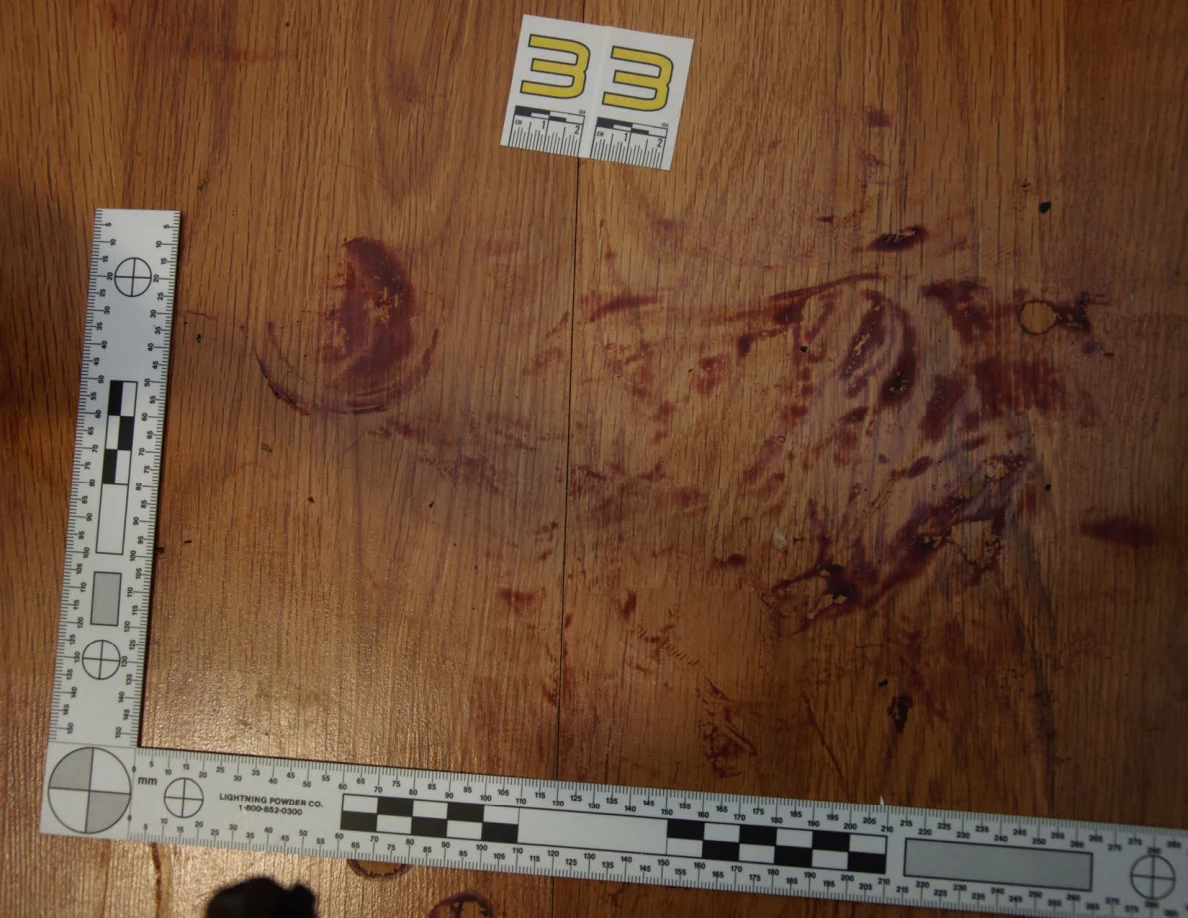 Reddish circular and smeared floor marks beside scale label 33 and measuring rulers.