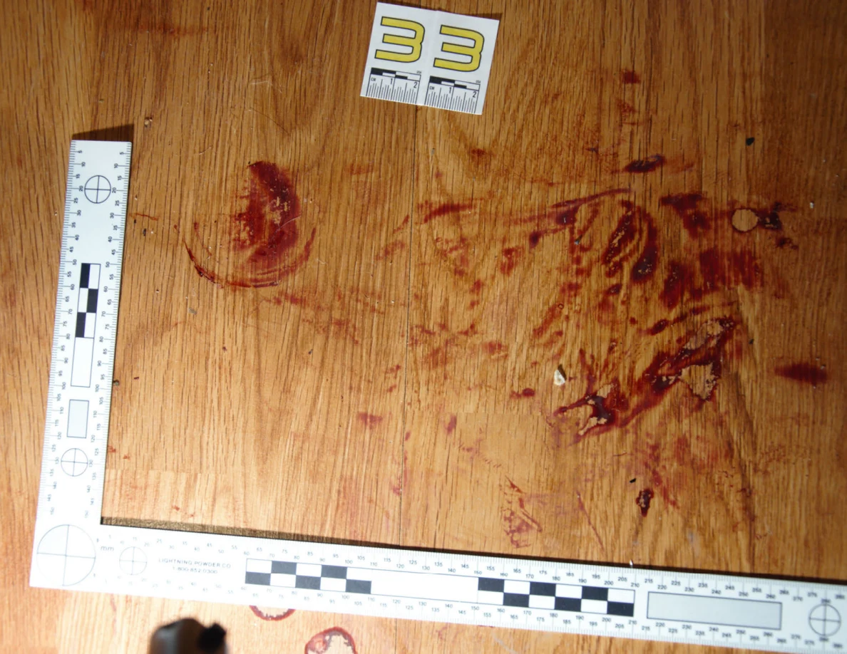 Reddish circular and smeared floor marks beside scale label 33 and measuring rulers.