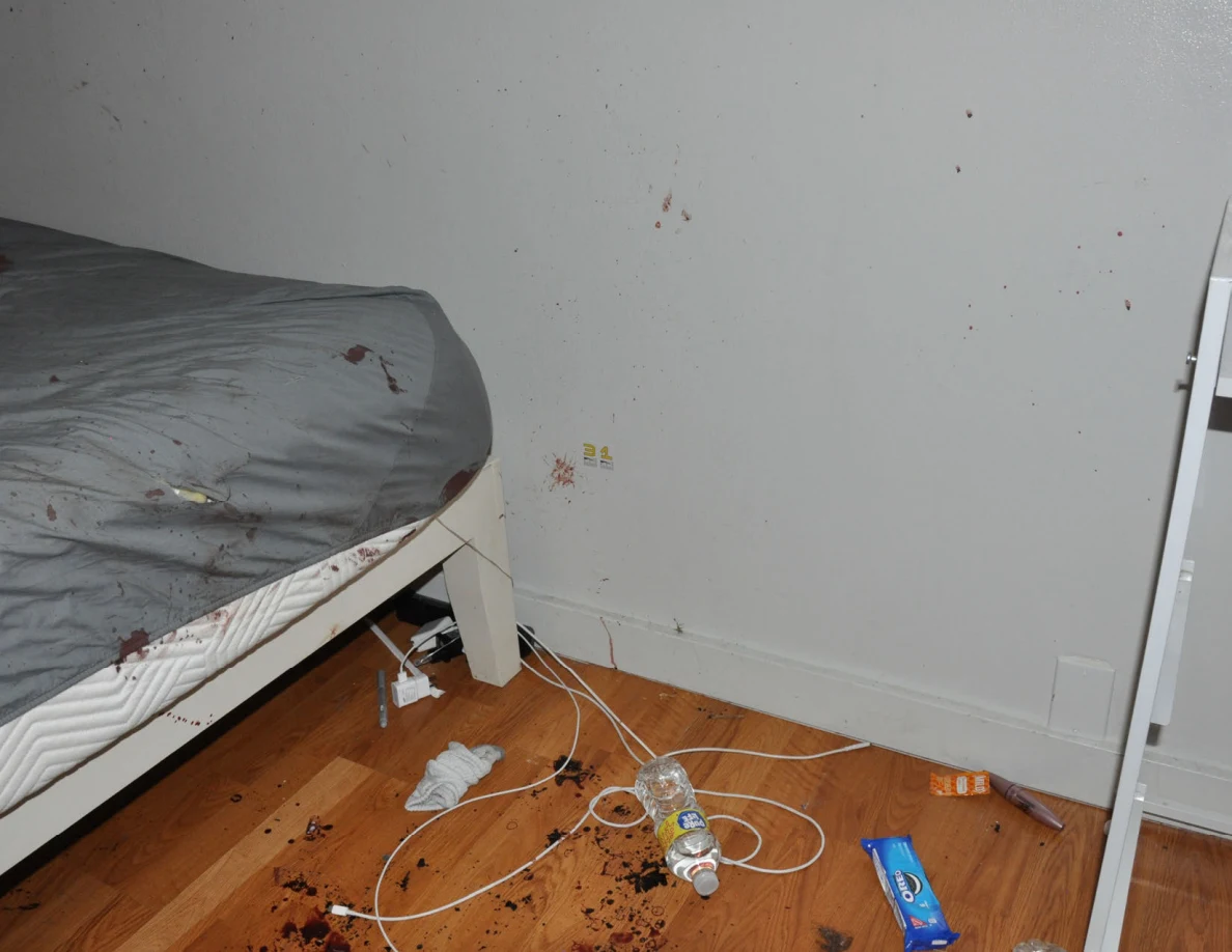 Reddish wall spots above cables and bottles beside a bed.