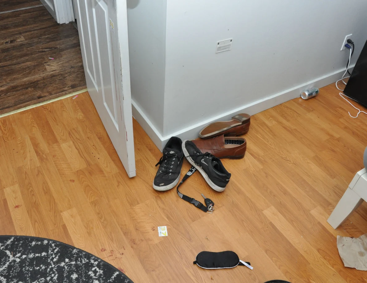 Footwear and a strap beside an open bedroom door and floor scale label.