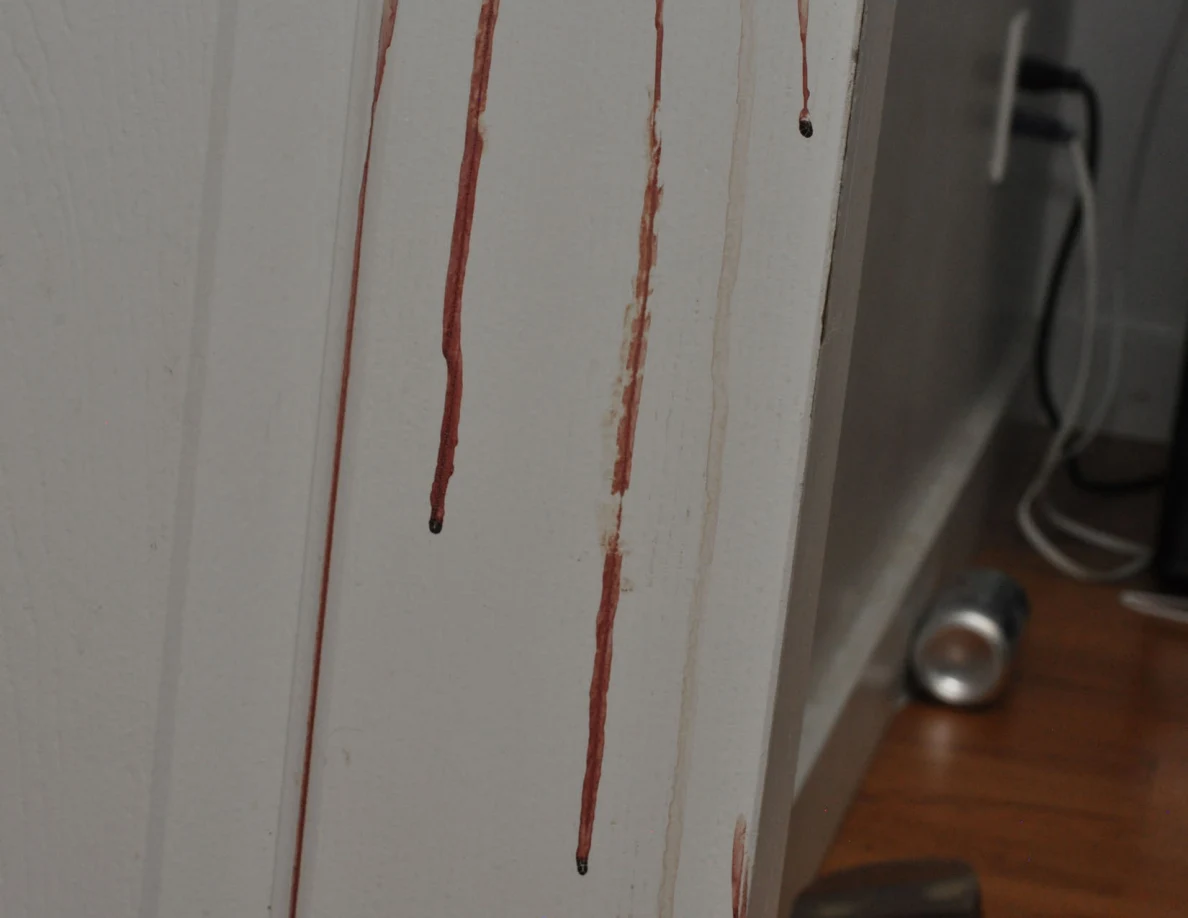 Close view of long reddish streaks on a white door.