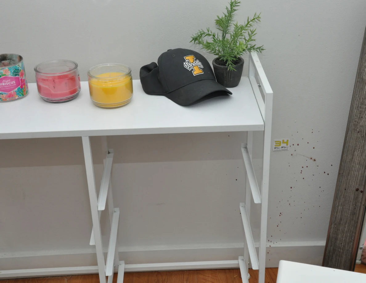 White cabinet frame with candles, a cap and plant beside wall scale label 34.