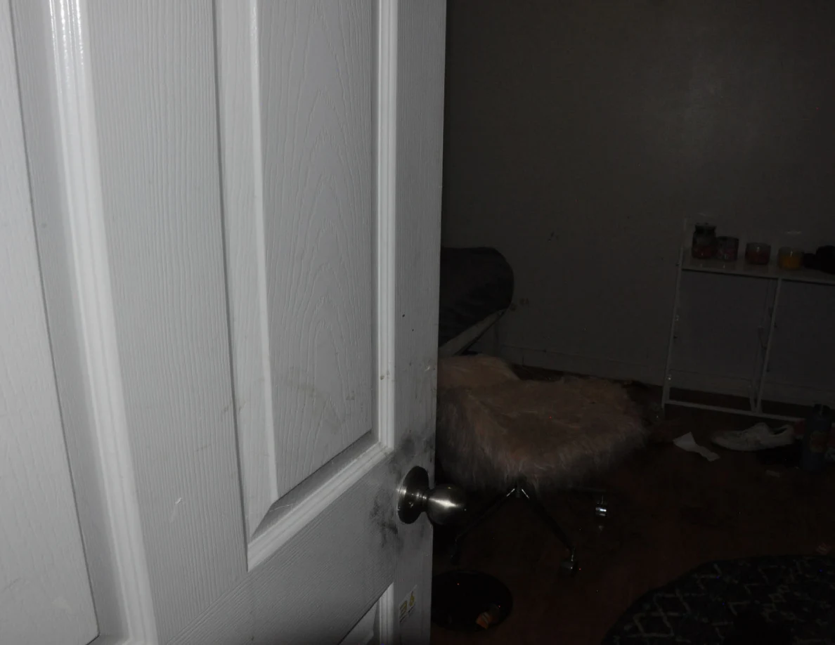 Dim bedroom view through an open white door.