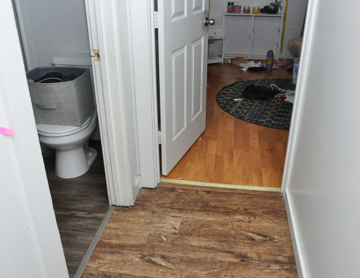 Hallway with visible bathroom toilet beside an open bedroom doorway.