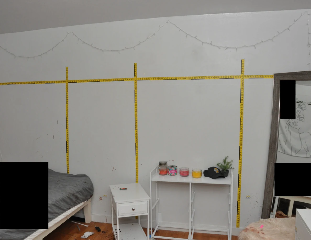 Yellow measuring scales across a bedroom wall above white furniture.