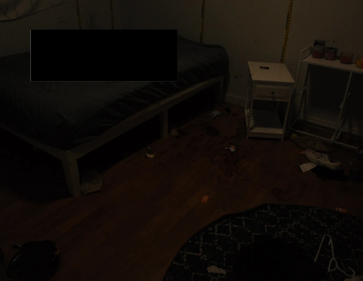 Dim partly redacted bed beside bedside furniture and marked flooring.