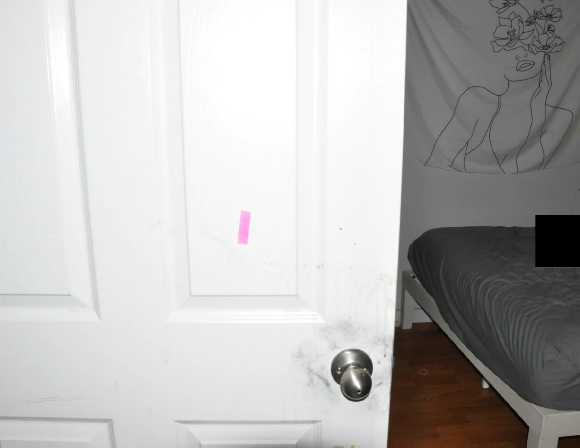White bedroom door with pink tape and dark smudges around its knob.