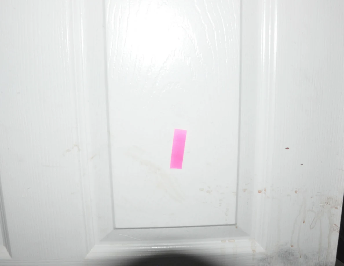 Pink tape on a white door panel with faint marks.