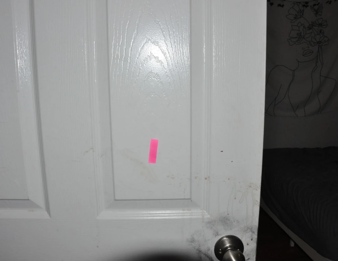 White door panel with pink tape and faint smears.