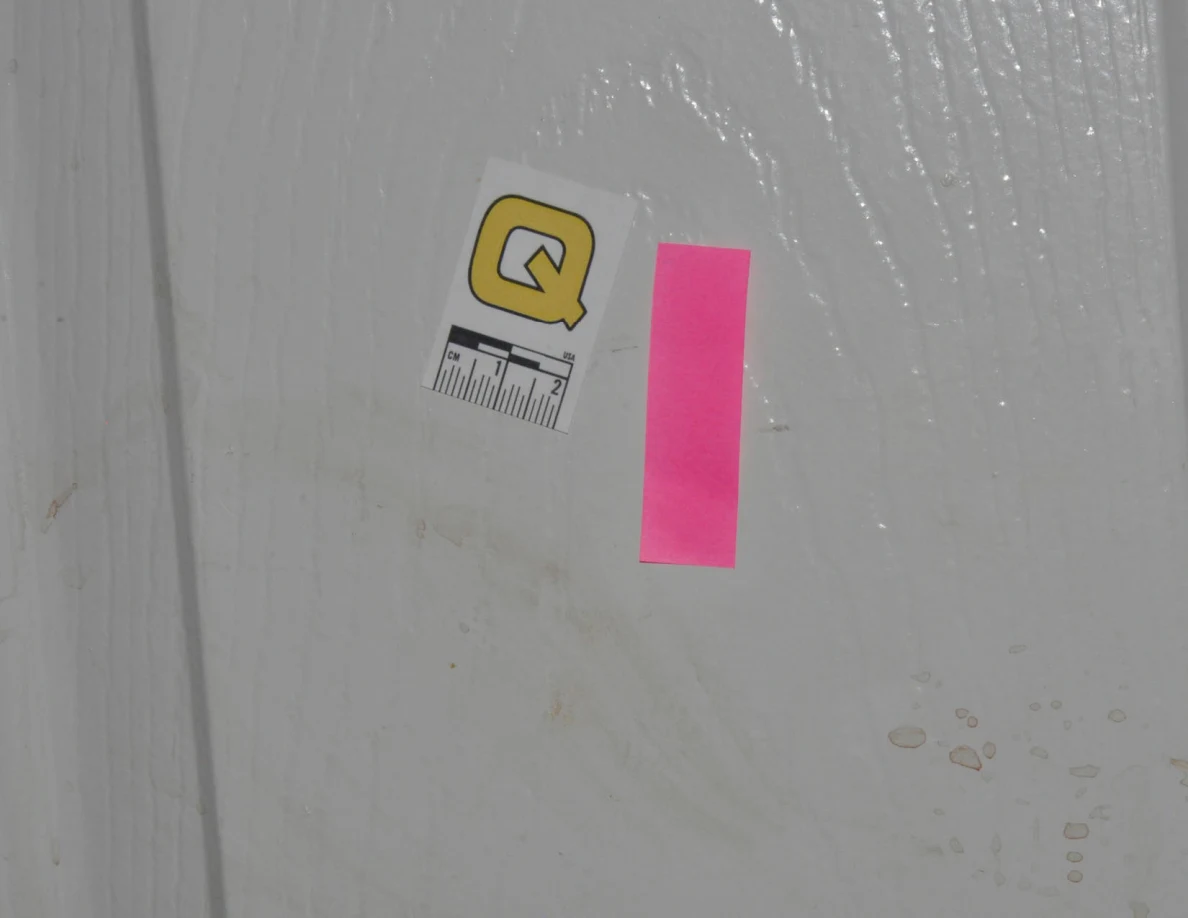 Close view of scale label Q and pink tape beside faint door marks.