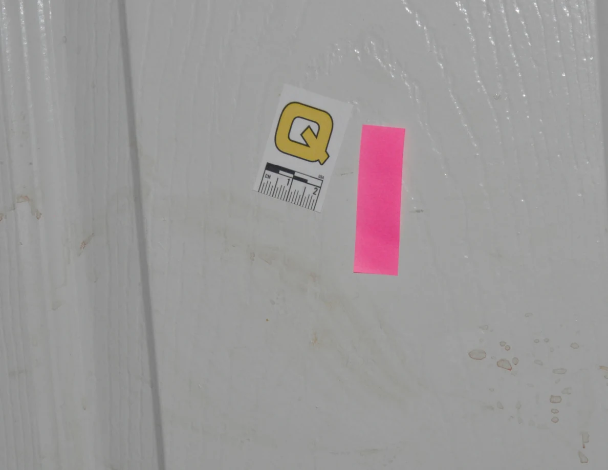 Close view of scale label Q and pink tape beside faint door marks.