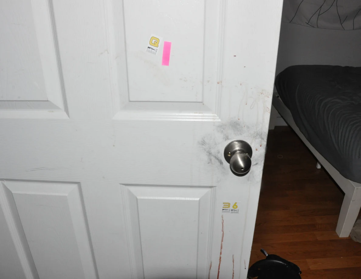 White door with Q label, pink tape, dark knob smudges and reddish streaks.