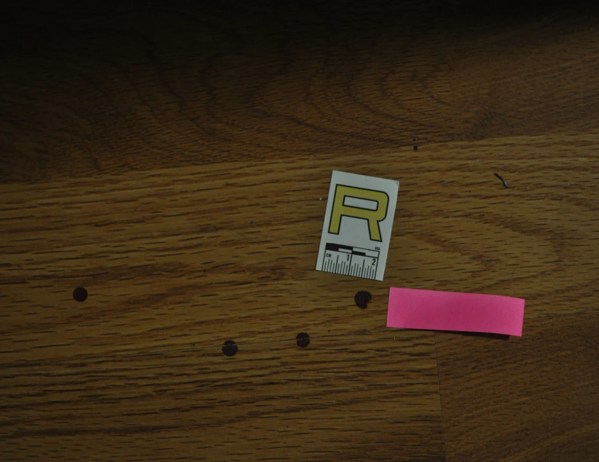 Dim view of floor spots beside scale label R and pink tape.