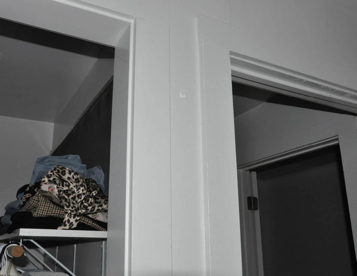 Upper closet and doorway frames with folded clothing on a shelf.