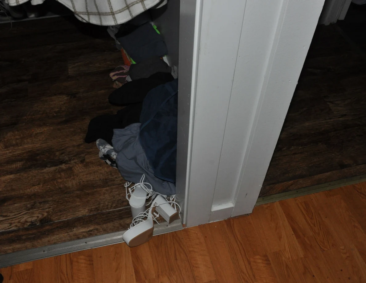 White strappy footwear and clothing at a closet threshold.