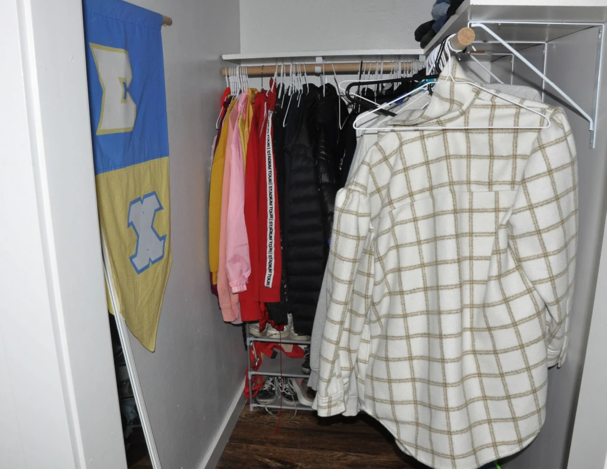 Closet clothing rails with a plaid garment and blue-and-yellow wall banner.