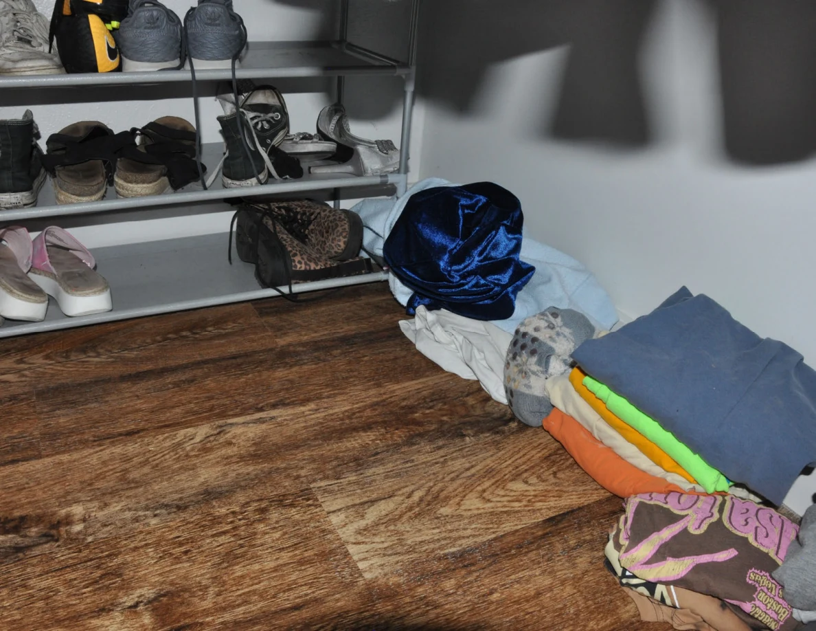 Shoe rack beside folded clothing and a blue fabric bundle on the floor.