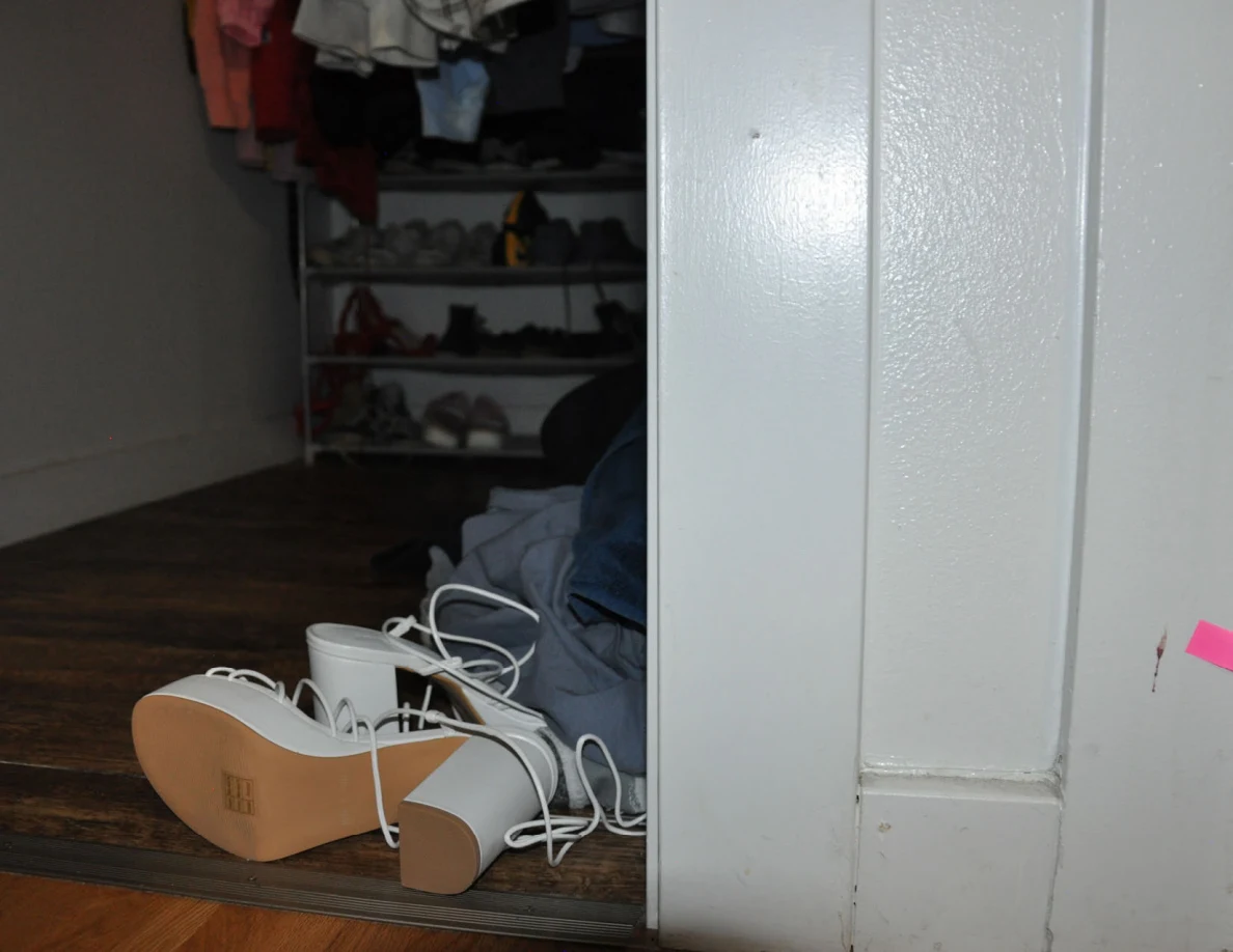 Closet frame with pink tape beside white footwear and a shoe rack.