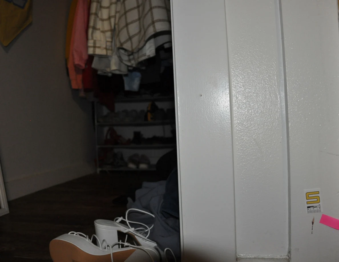 Scale label S and pink tape on a closet frame beside footwear.
