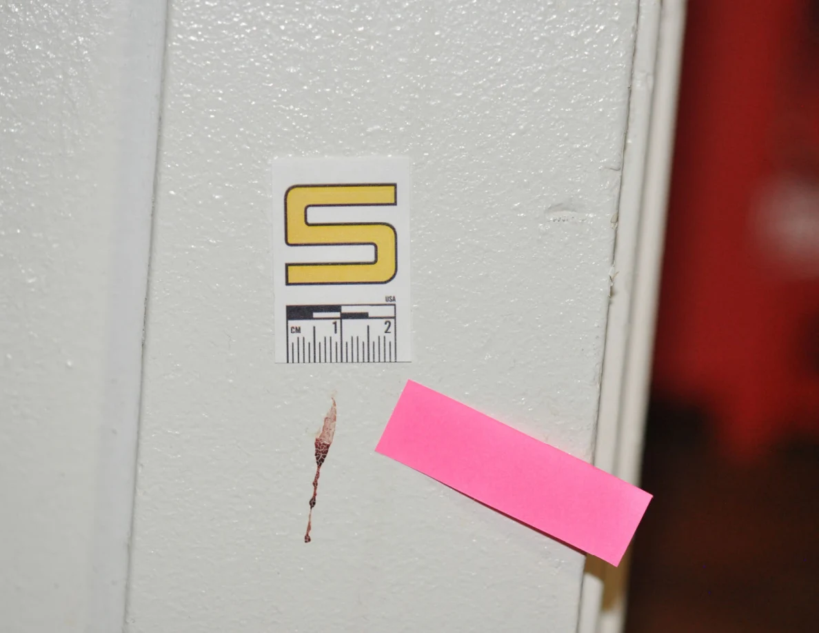 Close view of a reddish mark beside scale label S and pink tape on white door trim.