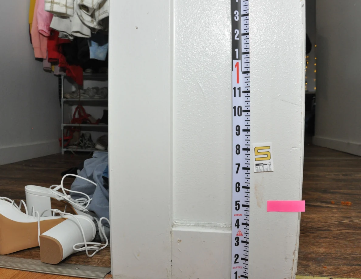 Vertical measuring ruler beside label S and pink tape on a closet frame.