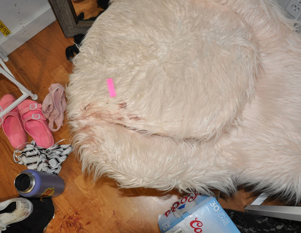 Pink tape on a fluffy chair with reddish marks beside pink footwear.