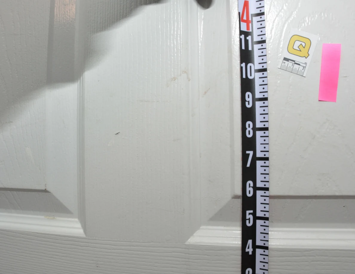 Vertical ruler beside label Q and pink tape on a white door.