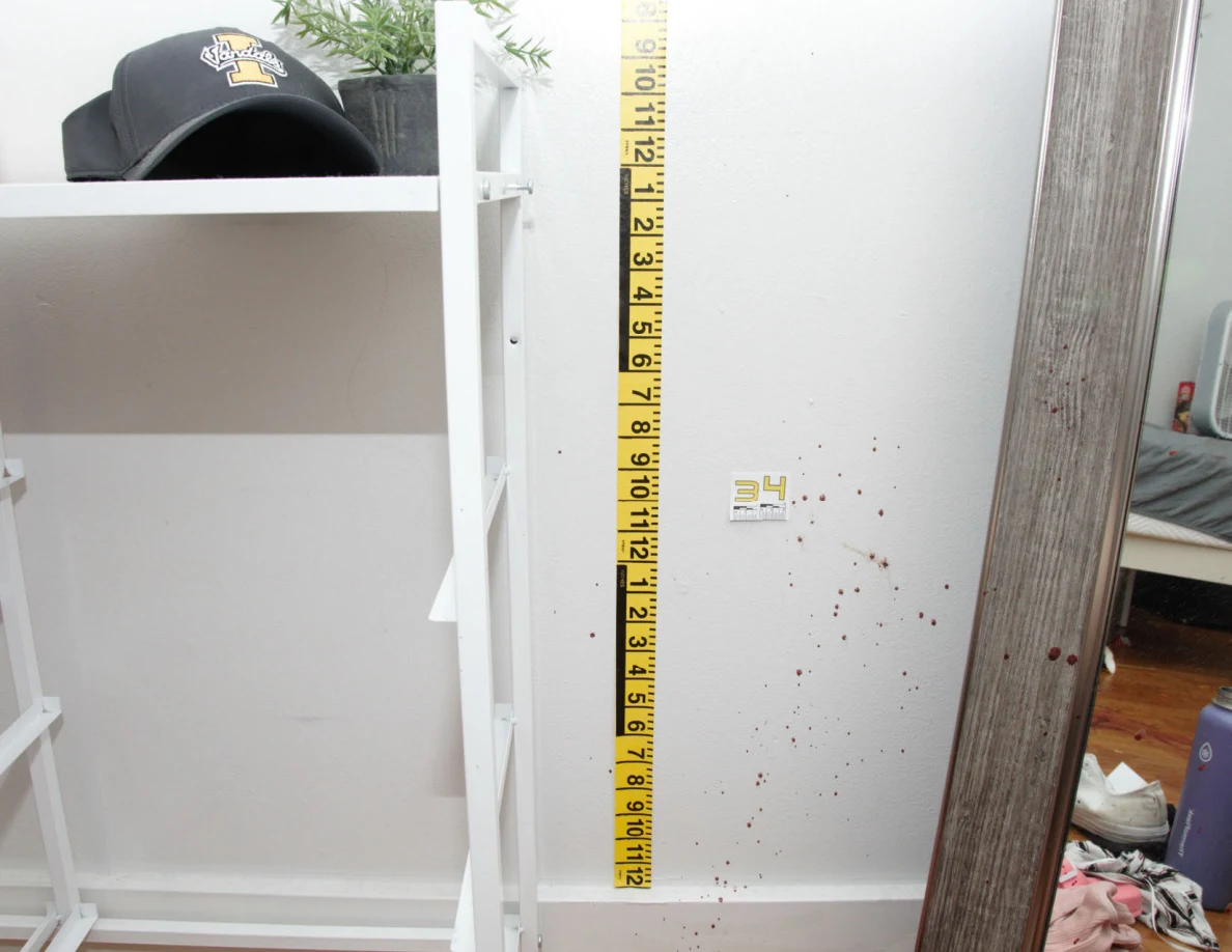 Yellow measuring tape beside reddish wall spots and scale label 34 near a mirror.