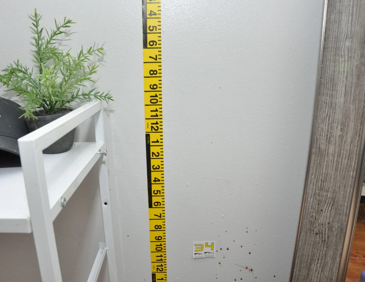 Yellow measuring tape beside reddish wall spots and scale label 34 near a mirror.