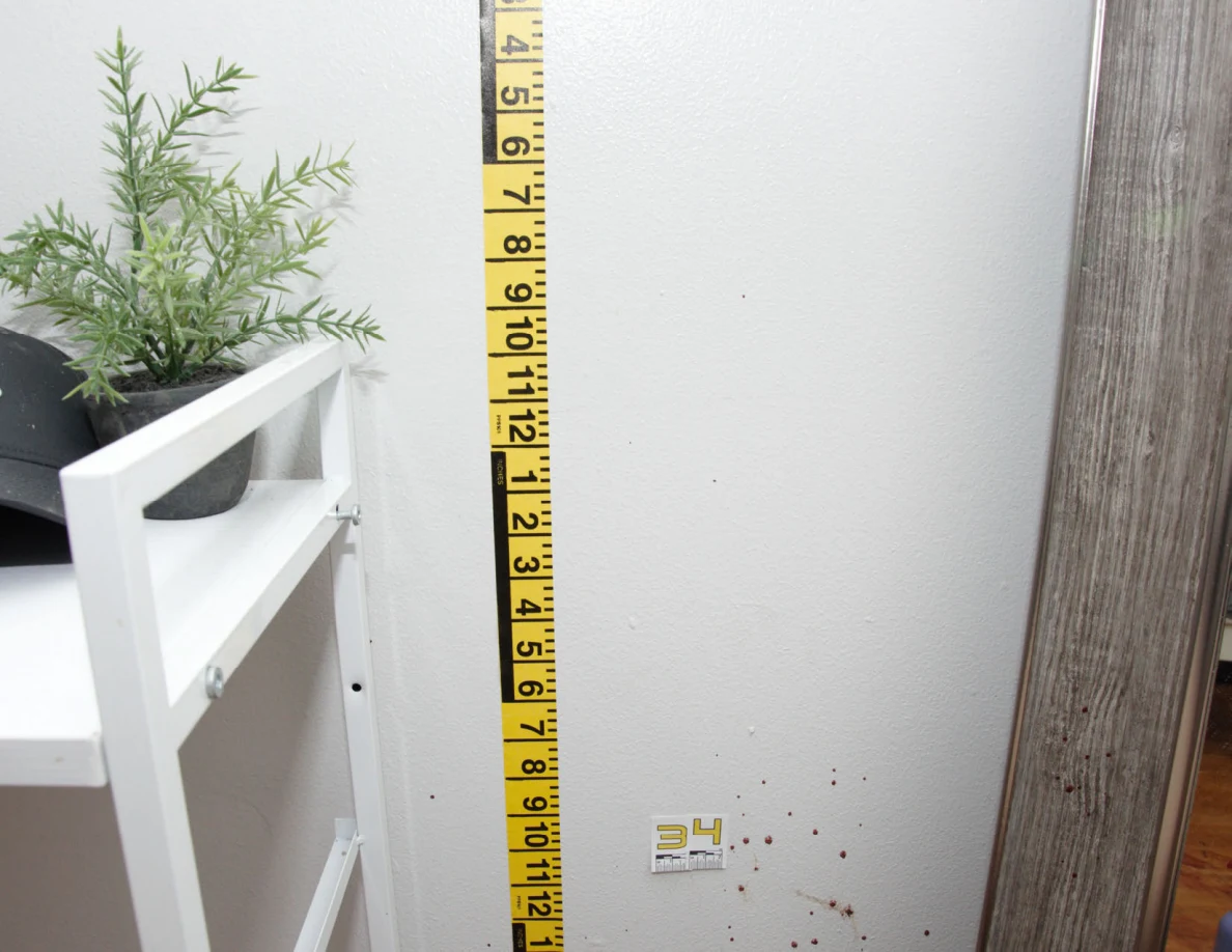 Yellow measuring tape beside reddish wall spots and scale label 34 near a mirror.