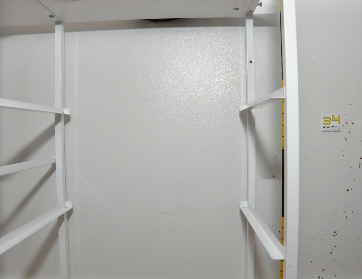 Empty white cabinet frame against a wall beside scale label 34.