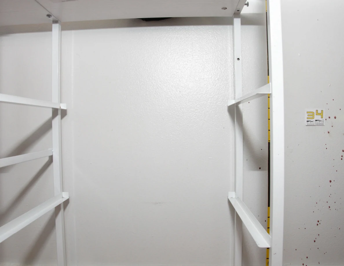 Empty white cabinet frame against a wall beside scale label 34.