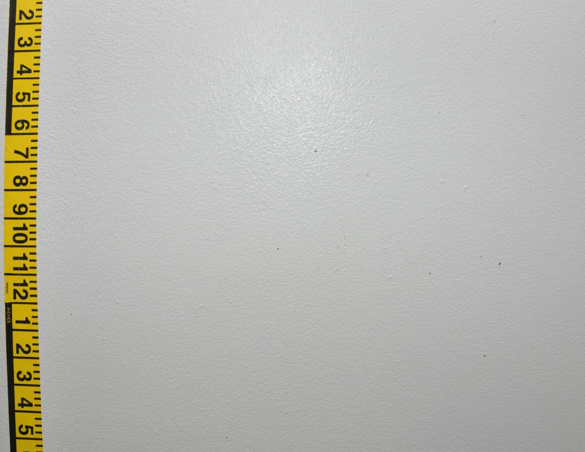 Vertical yellow measuring tape beside small wall marks.