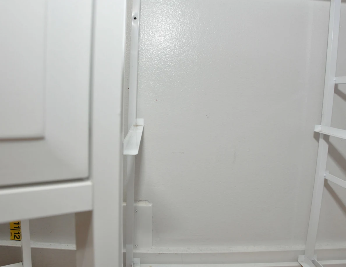 Pale wall behind white cabinet supports.