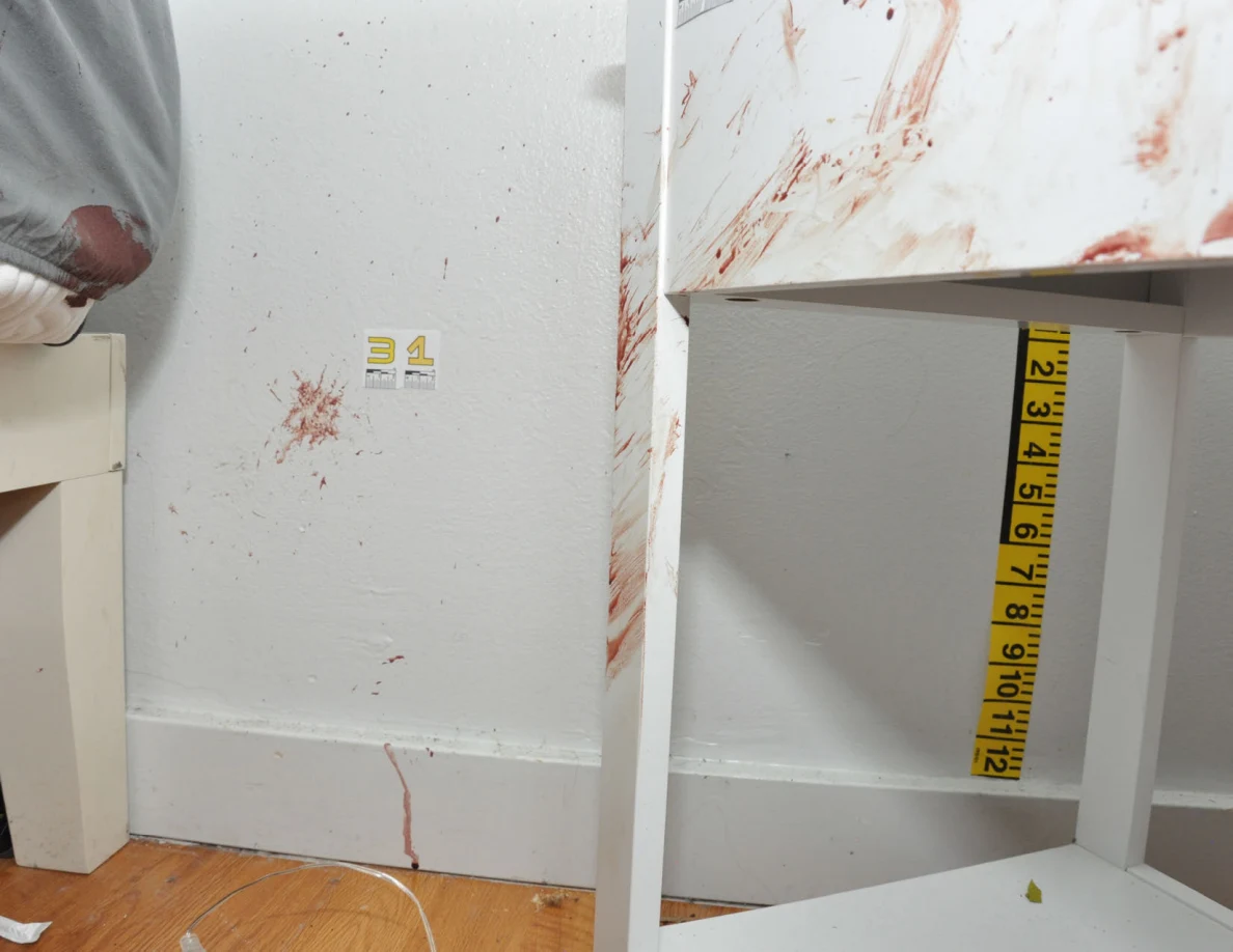 Label 31 beside reddish wall spots between a bed and marked white cabinet.