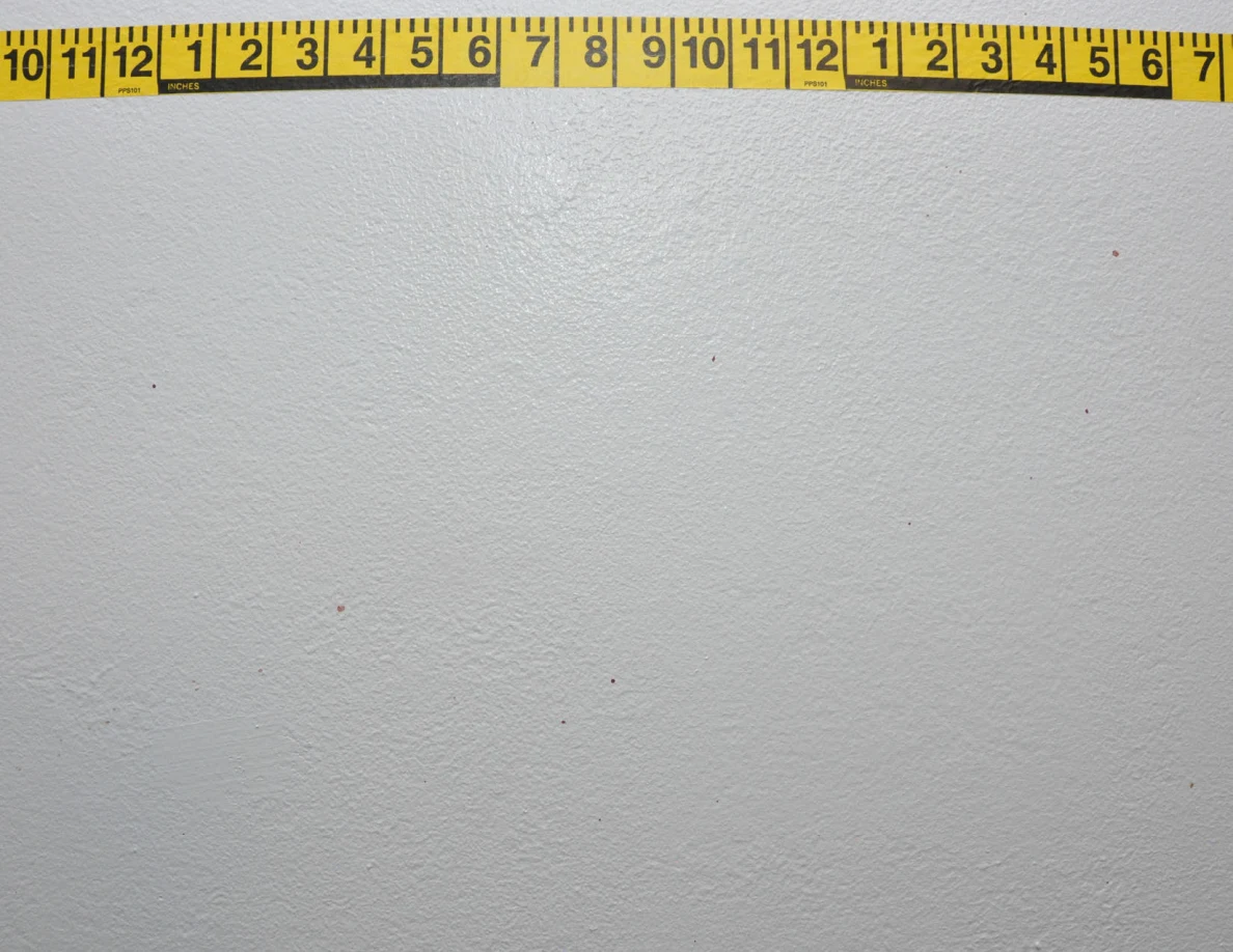 Horizontal yellow measuring tape across a pale wall.
