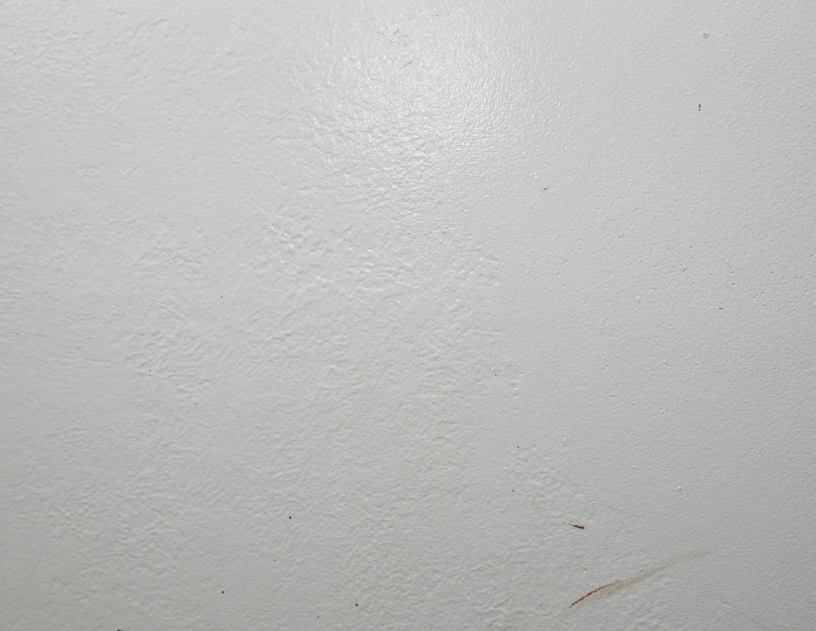 Close view of a faint reddish streak on a pale wall.