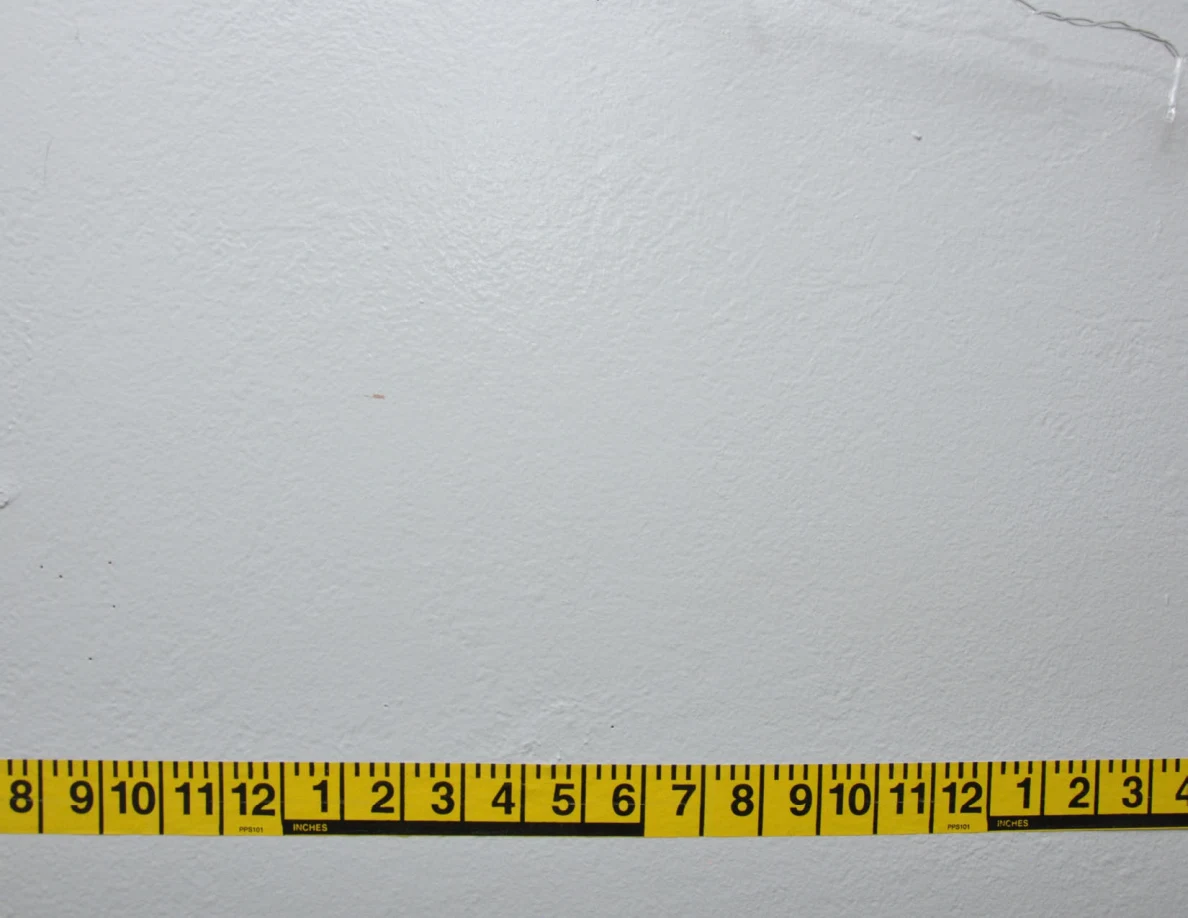 Horizontal yellow measuring tape across a pale wall.