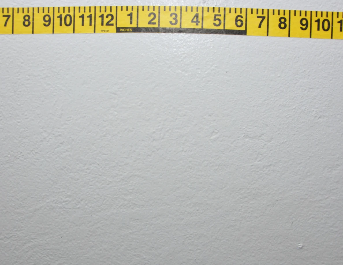 Horizontal yellow measuring tape across a pale wall.