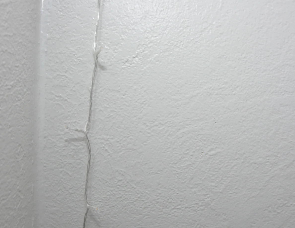 String-light cable against a pale textured wall.